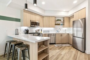A modern kitchen with a central island, stainless steel appliances, and wooden cabinetry.