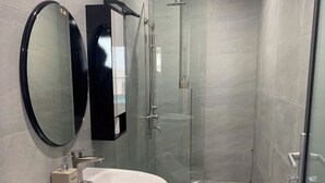 Et moderne badeværelse med et stort spejl, en vask, et toilet og en brusekabine med glasvægge.