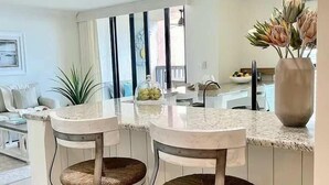 Een moderne keuken met een centraal eiland, barkrukken en een eethoek.