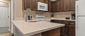 A kitchen with a sink, a microwave, a stove, and wooden cabinets.