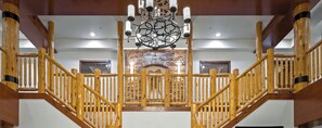 A wooden staircase with a stone wall and a chandelier.