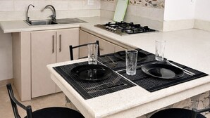 A kitchen with a central island, bar stools, a gas stove, and a backsplash with coffee-themed tiles. - Nova Suite : Modern and cozy in the center of Guayaquil (Guayaquil)