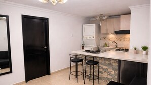A modern kitchen with a white countertop, two bar stools, a black bench, and a stone backsplash. - Nova Suite : Modern and cozy in the center of Guayaquil (Guayaquil)