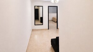 A narrow hallway with a tiled floor, white walls, and a black sofa. - Nova Suite : Modern and cozy in the center of Guayaquil (Guayaquil)