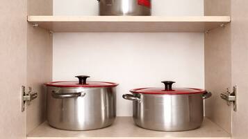Un armario de cocina con ollas de acero inoxidable sobre estantes.