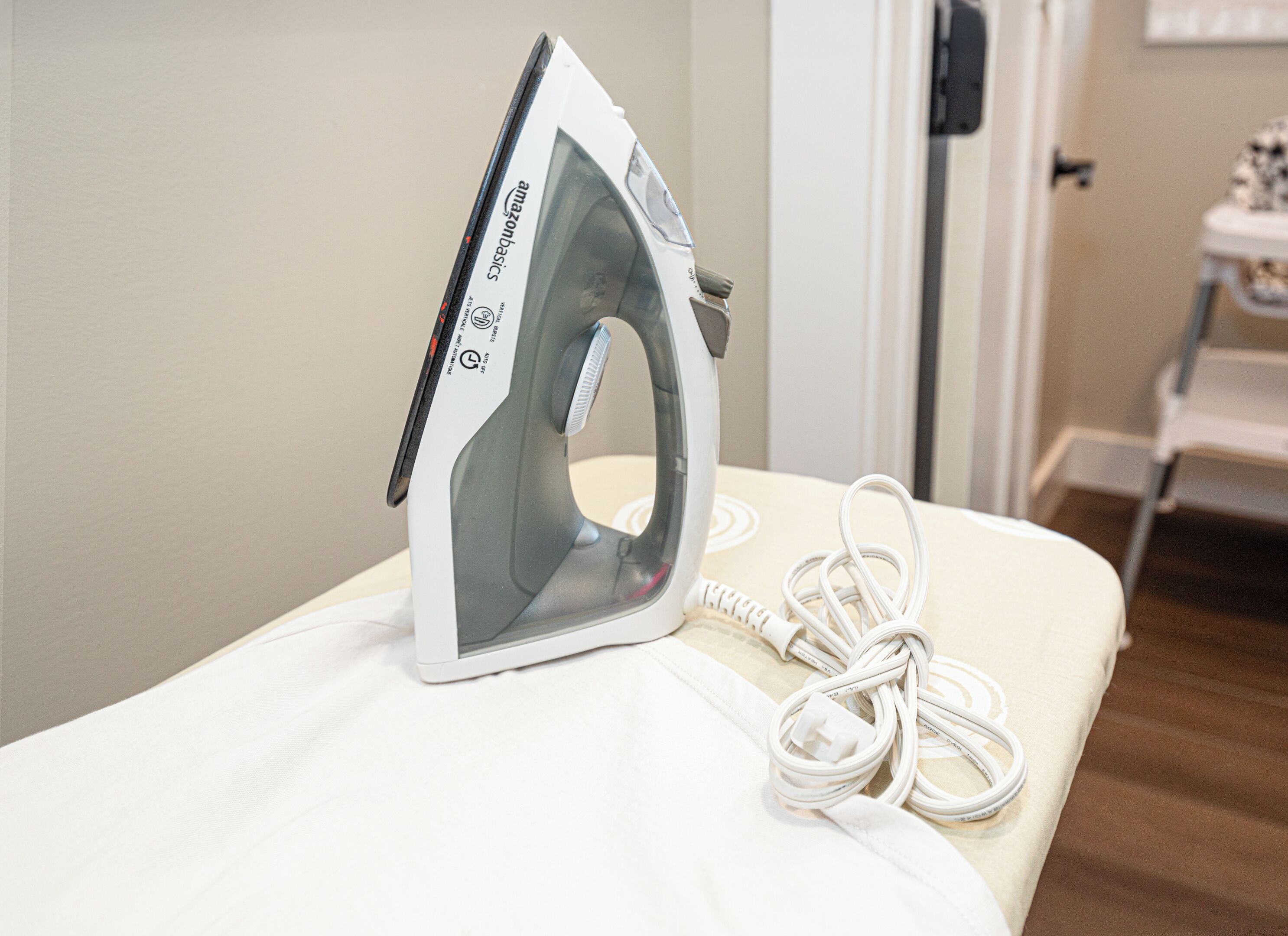 An iron on a bed with a white cable.