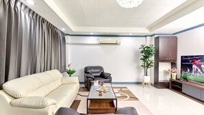 A living room with a sofa, a coffee table, a TV, and a plant. - TEN-Place Srinakarin (Bangkok)