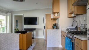 Een moderne keuken met een inbouwoven, een koffieapparaat en een aan de muur bevestigde televisie.