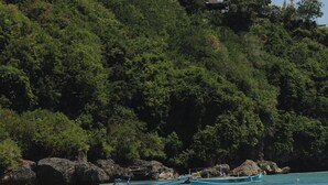A beach with clear water, a person swimming, and boats. - La Brava  (Pecatu)