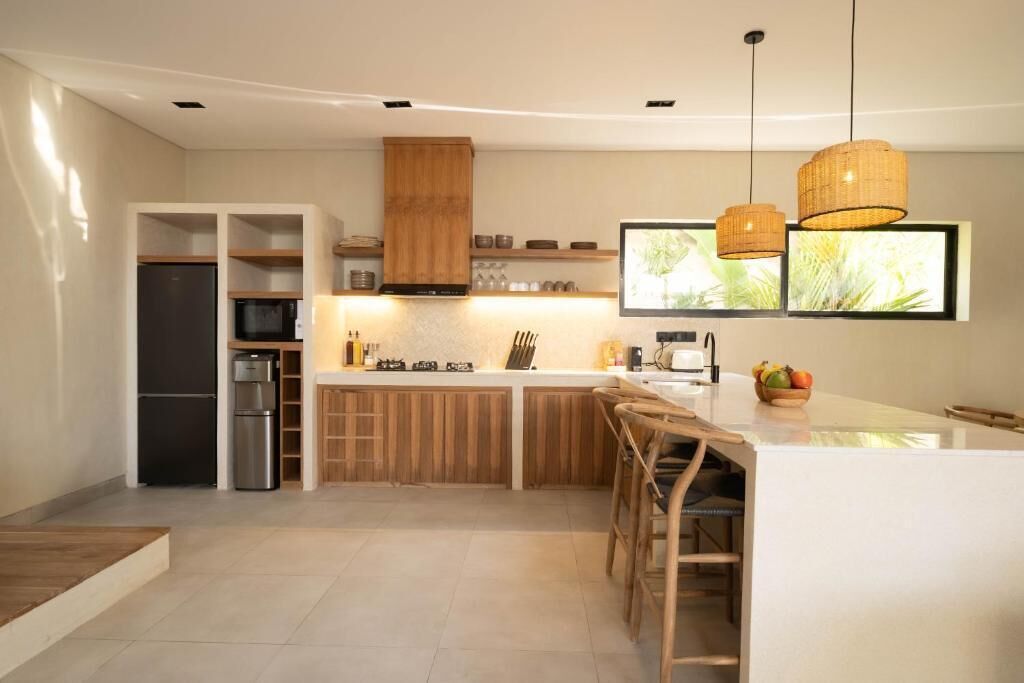 Una cocina moderna con una isla central, armarios de madera e iluminación colgante.
