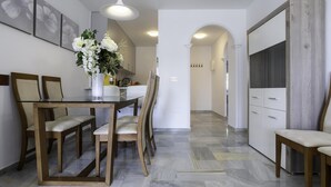 Una cocina moderna con una mesa de comedor, sillas, un jarrón de flores y un televisor.