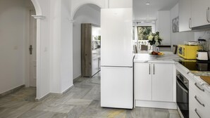 Una cocina moderna con armarios blancos, una isla central y un horno empotrado.