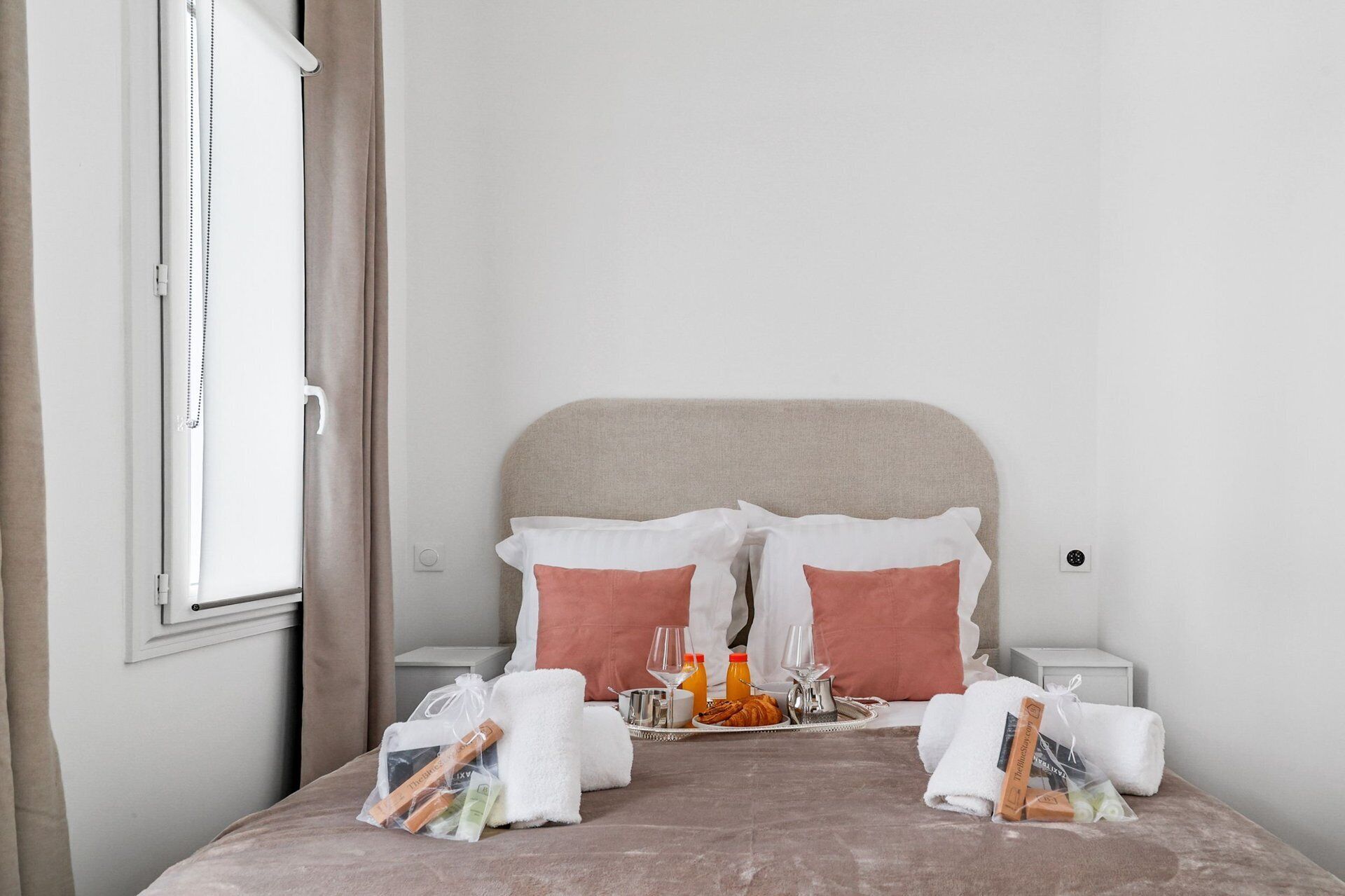 A neatly made bed with pillows, a tray with breakfast items, and toiletries.