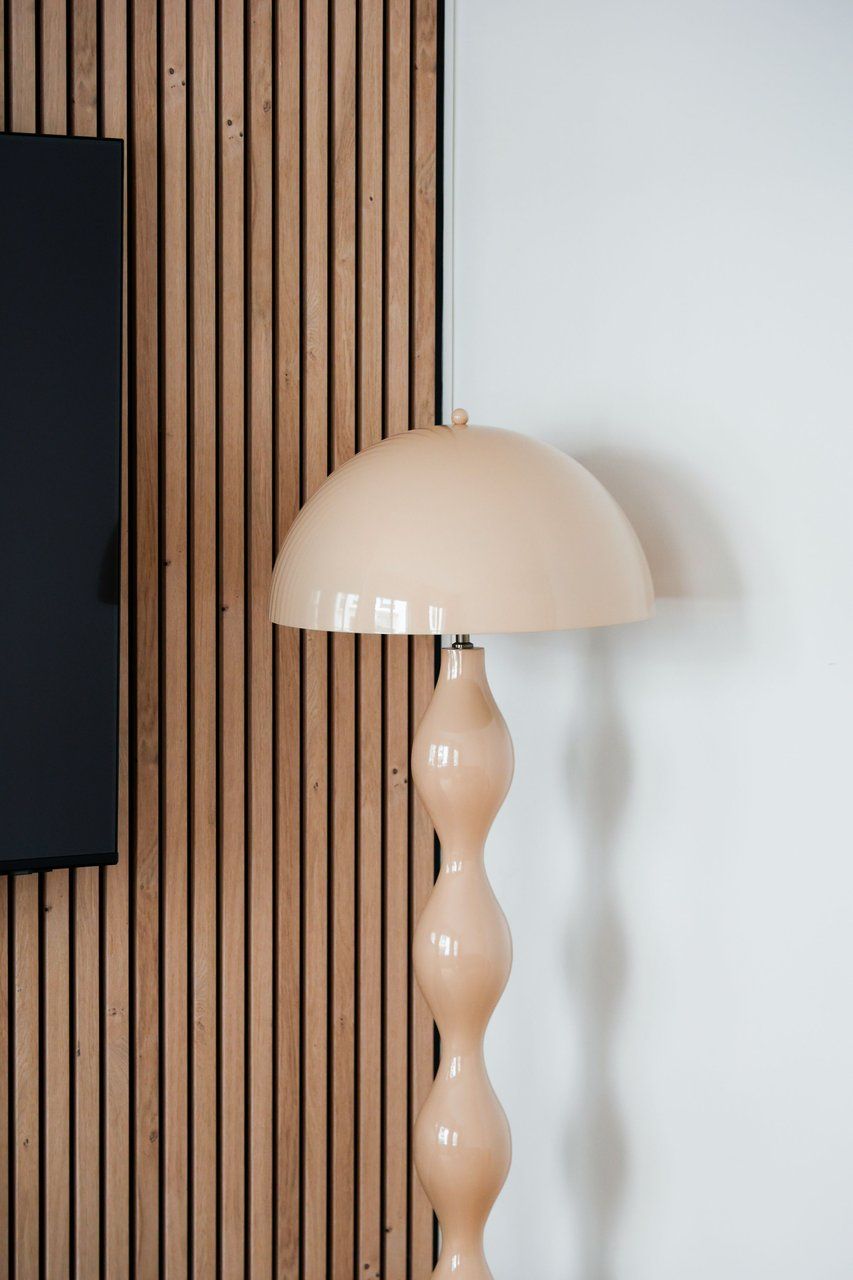 Une lampe au design original, placée devant un mur en bois.