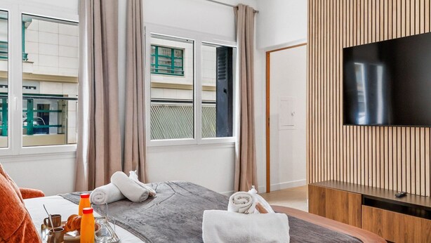 A hotel room with a bed, a TV, a window with curtains, and a tray with breakfast items. - TheBlueStay 261 - Stunning Designer Apt - Paris 15 (Paris)
