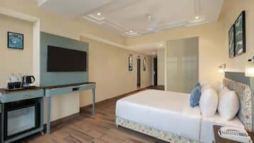 A hotel room with a bed, a desk with a flat-screen TV, a coffee maker, and a telephone.