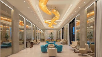A spacious lobby with modern furniture, a unique spiral chandelier, and glass partitions.