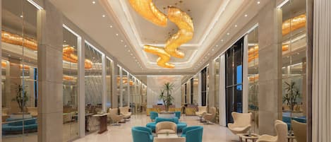 A spacious lobby with modern furniture, a unique spiral chandelier, and glass partitions.