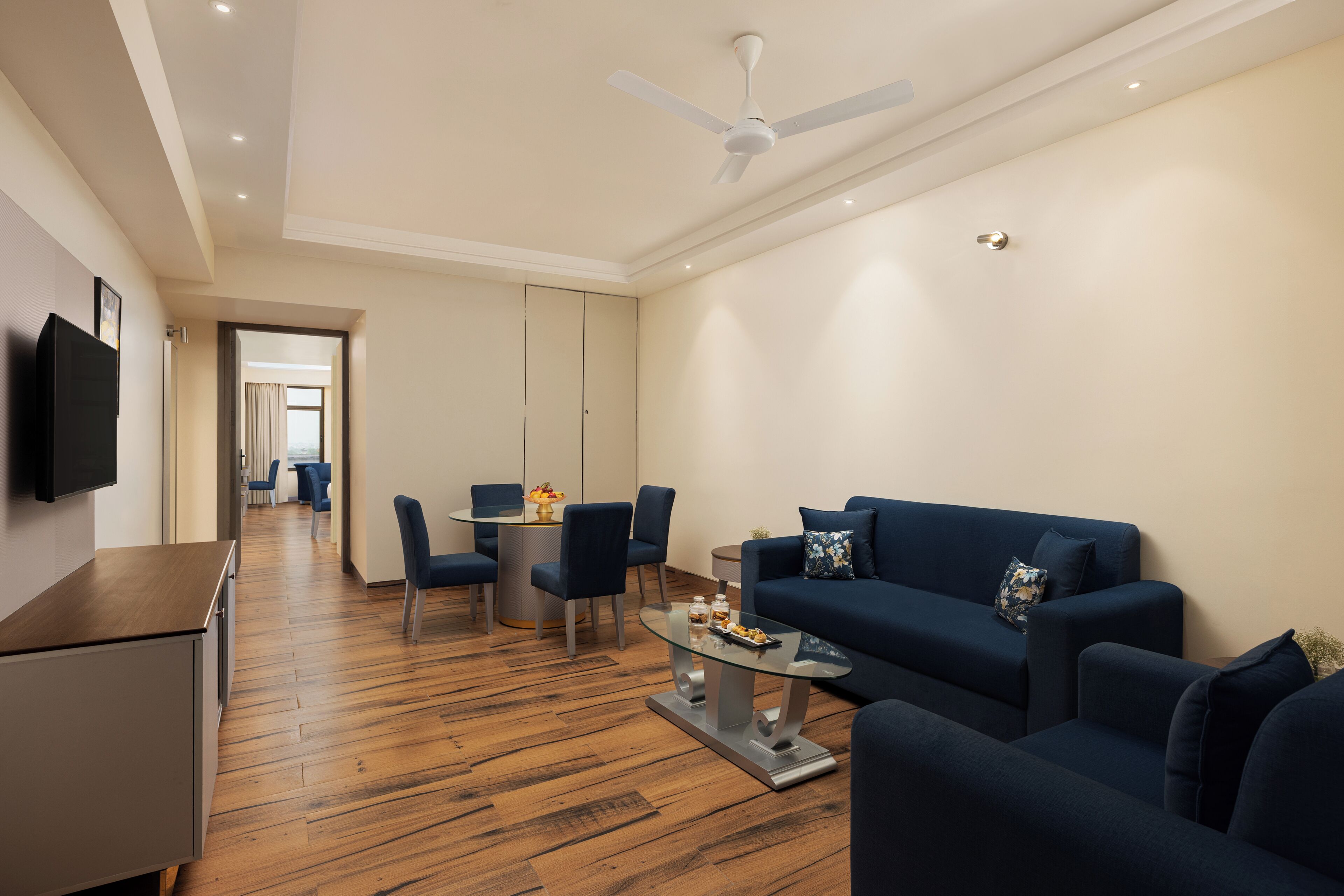 Una sala moderna con un sofá, sillas, una mesa de centro y un televisor montado en la pared.