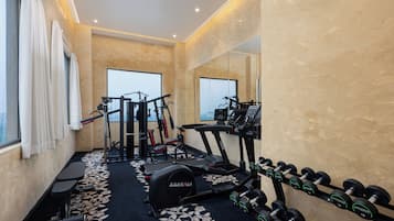 Un gimnasio con equipo de ejercicio, cinta de correr y mancuernas.