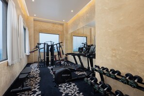 A gym with exercise equipment, a treadmill, and dumbbells. - Essentia Luxury Hotel and Convention (Kamptee)