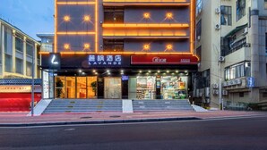 Un hotel de varios pisos con fachada moderna, ventanas iluminadas y una entrada visible con señalización.
