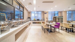 Un moderno comedor de hotel con un sistema de buffet, disposición de mesas y vistas a la ciudad a través de amplias ventanas.