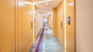 Un pasillo de hotel con puertas de madera, piso alfombrado y una larga extensión.