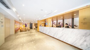 Zona de recepción de un hotel con un mostrador de mármol, un cartel de 'No Fumar' y un letrero que indica 'Recepción'.