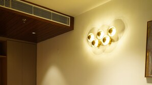 A modern living room with a wooden ceiling, a built-in heater, and a wall-mounted light fixture. - Luxe Manor (Kharar)