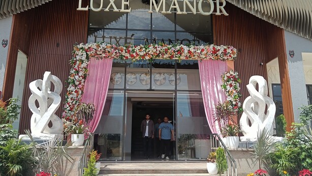 A building entrance with a sign reading 'LUXE MANOR,' featuring a modern design with vertical slats and a decorative archway. - Luxe Manor (Kharar)