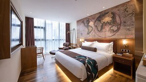 A hotel room with a large bed, a desk, a chair, a map on the wall, and a window with curtains. - ELITE James Joyce Coffetel Hotel Guangzhou Pedestrian Street Beijing Lu Metro Station Branch - Free Deliver Service to Canton Fair Complex During Canton Fair Period (Guangzhou)