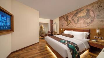 Une chambre d’hôtel avec un grand lit, un plancher en bois, une carte du monde accrochée au mur, un téléviseur fixé au mur et une table de chevet avec une lampe.