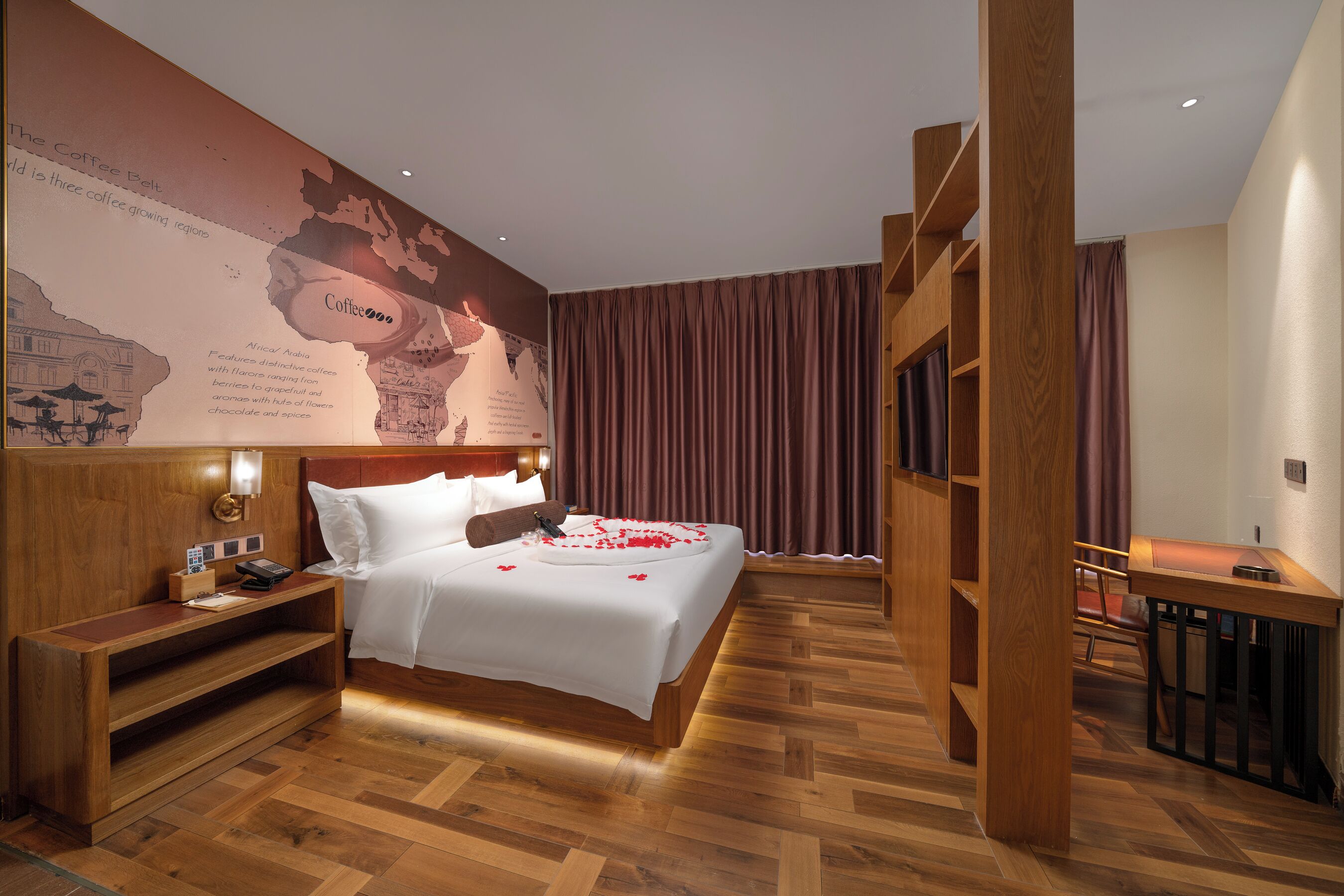Hotelkamer met een groot bed, een houten bureau, een nachtkastje en een kaart aan de muur.
