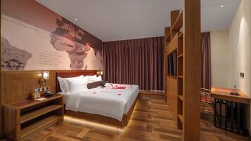 Hotelkamer met een groot bed, een houten bureau, een nachtkastje en een kaart aan de muur.