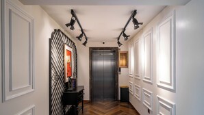 A hallway with a wooden floor, an elevator, and a wall-mounted light fixture. - ELITE James Joyce Coffetel Hotel Guangzhou Pedestrian Street Beijing Lu Metro Station Branch - Free Deliver Service to Canton Fair Complex During Canton Fair Period (Guangzhou)