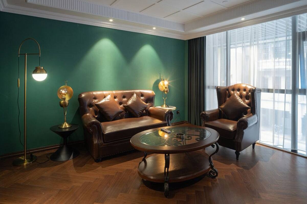 A room with a leather sofa, a leather armchair, a glass coffee table, and two floor lamps.