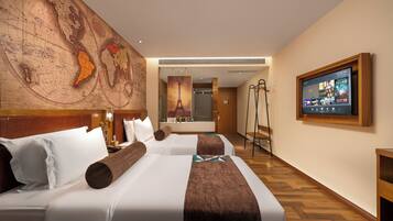 A hotel room with a large world map, a television, two beds, a wooden floor, and a mirror.