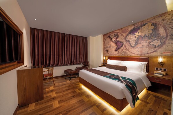 A hotel room with a large bed, wooden flooring, a desk, a chair, a map on the wall, and a window with curtains. - ELITE James Joyce Coffetel Hotel Guangzhou Pedestrian Street Beijing Lu Metro Station Branch - Free Deliver Service to Canton Fair Complex During Canton Fair Period (Guangzhou)