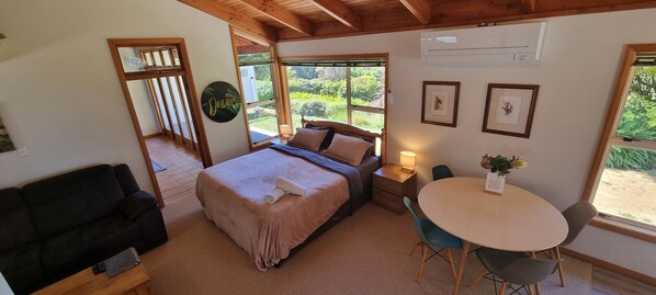 Un dormitorio con cama, sofá, mesa y ventana con vistas a zonas verdes.