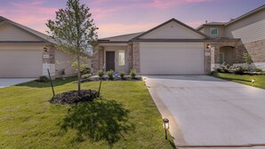 A residential building with a brick facade, a front lawn, and a garage. - Brand-New Home - Near Fort Sam & Randolph - Safe (Converse)
