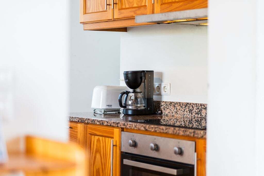Una cocina con armarios de madera, cafetera y tostadora.