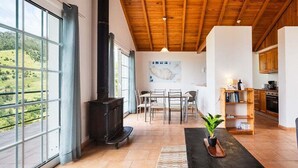 Un'ampia stanza con una grande finestra, un camino, un'area pranzo e una cucina.