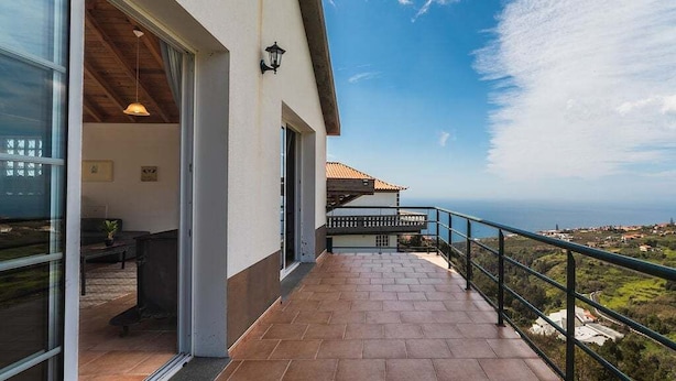 Un balcone con vista sul mare, un corrimano e l'ingresso di un edificio.