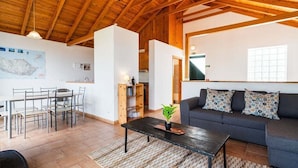 Un'ampia zona giorno con tavolo da pranzo, divano e soffitto in legno.