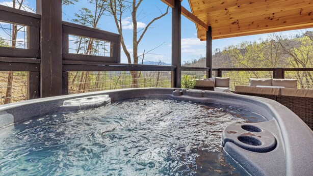 Una vasca idromassaggio con un pontile in legno e vista sugli alberi.