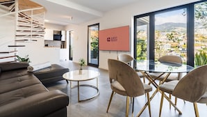 Una sala moderna con una escalera en espiral, un comedor con sillas y un amplio ventanal con vistas.