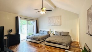 Ein Schlafzimmer mit zwei Betten, einem Deckenventilator, einem Fernseher und einem Fenster.