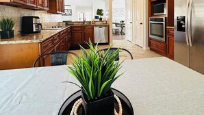 Eine moderne Küche mit Holzschränken, einem Edelstahlkühlschrank und einem Essbereich mit Tisch und Stühlen.