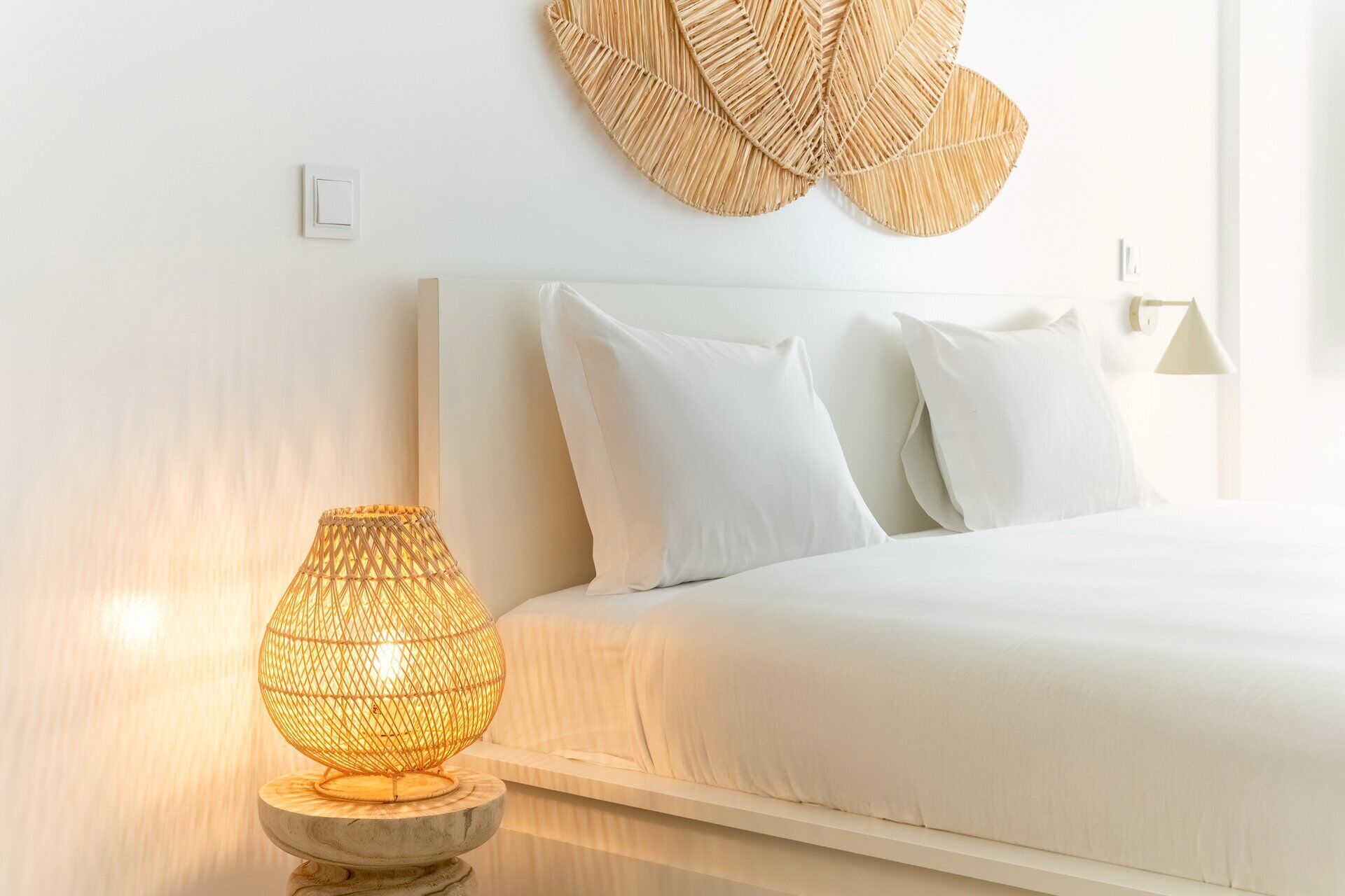 A neatly made bed with white linens, a textured wall hanging above, and a spherical lamp on a wooden stand beside the bed. - GuestReady - Charming duplex in the Alfama heart (Lisbon)